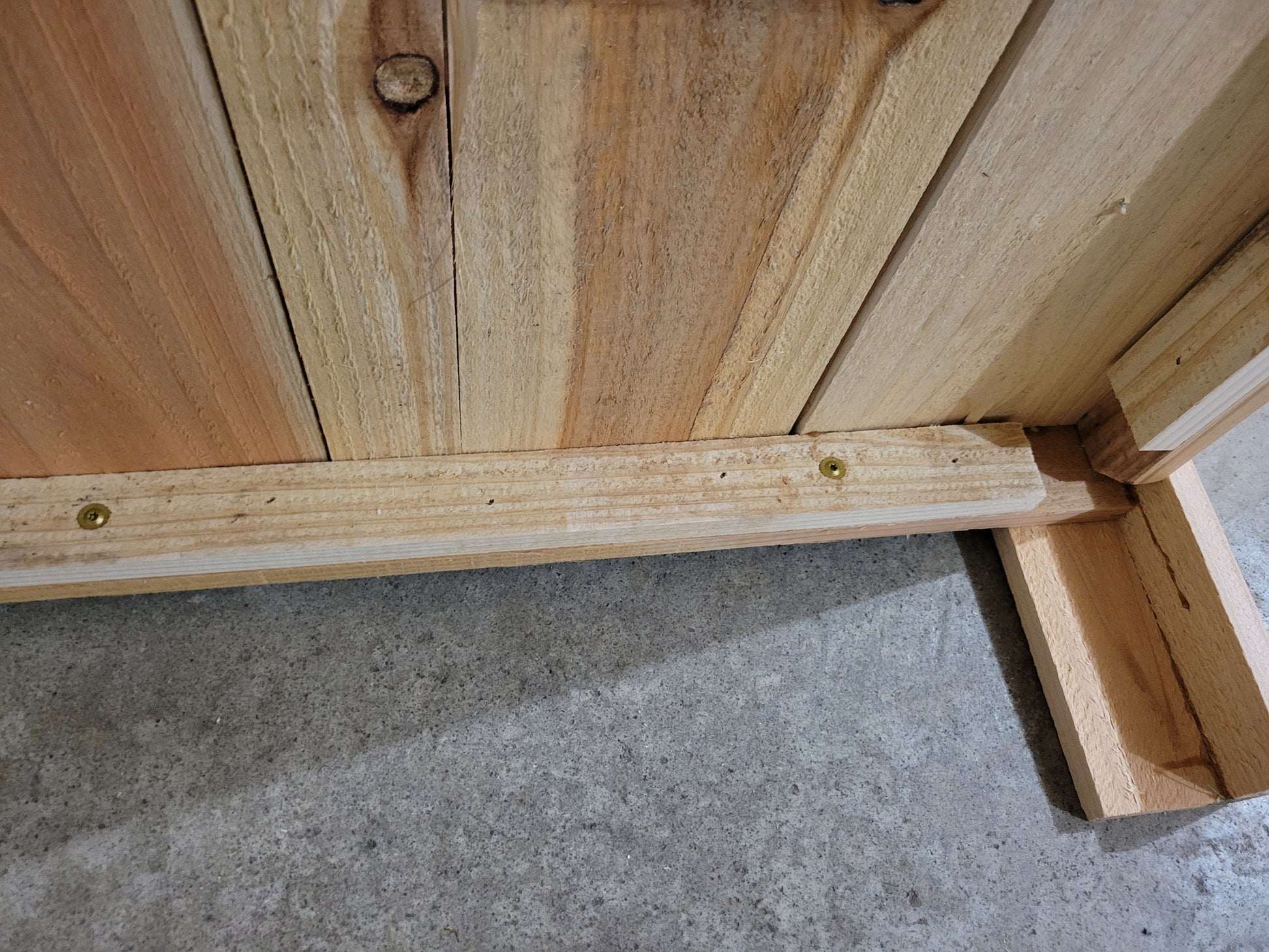 Close-up of wooden structure with visible screws on a concrete floor
