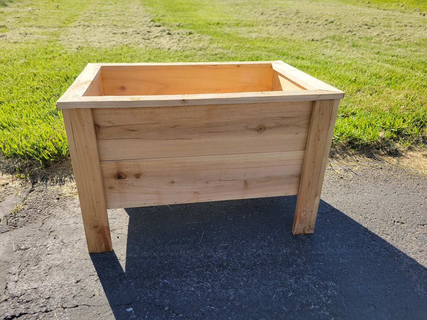 Wooden planter box on a paved surface with grass in the background in Marysville Ohio
