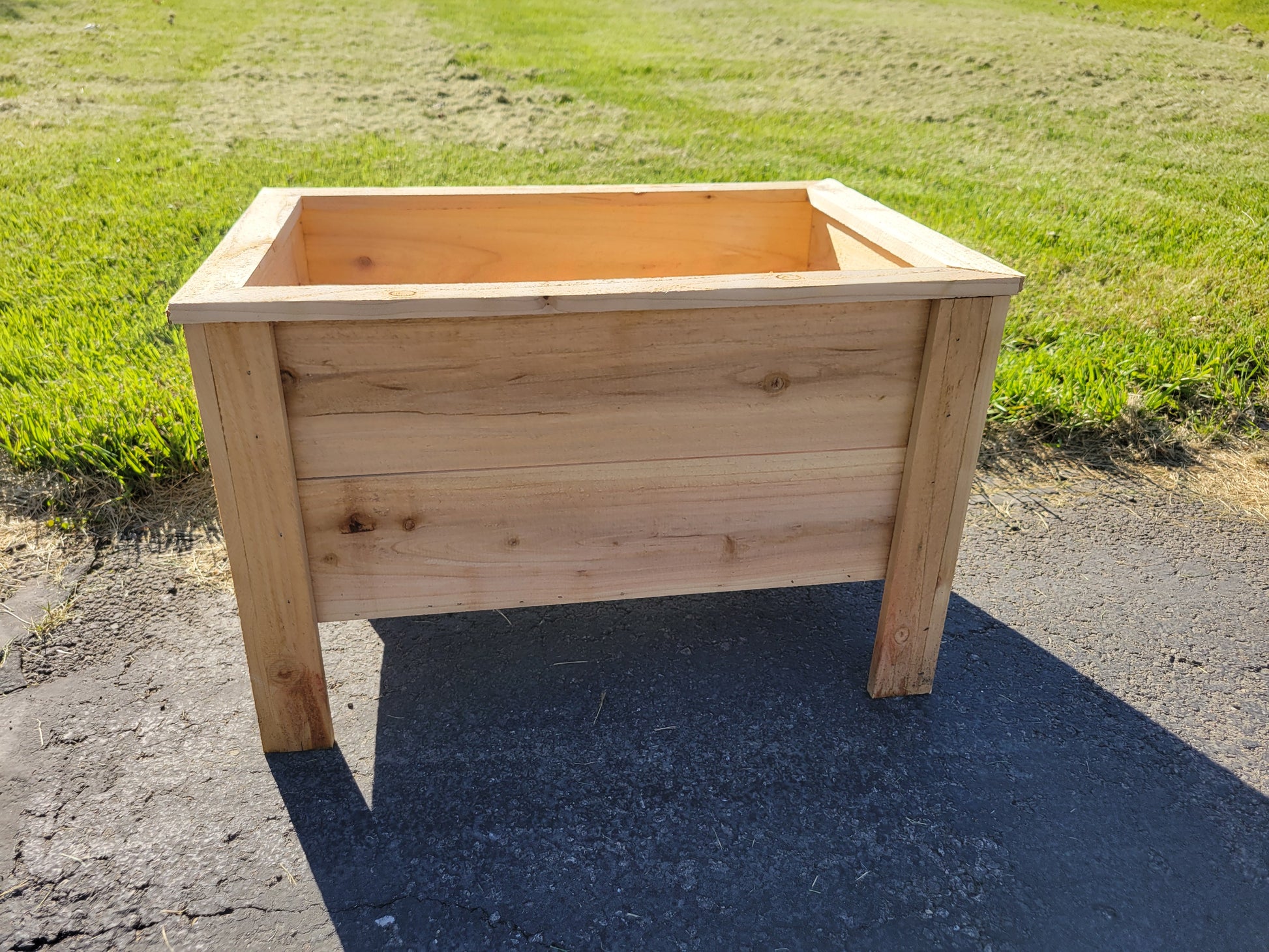 Wooden planter box on a paved surface with grass in the background in Marysville Ohio