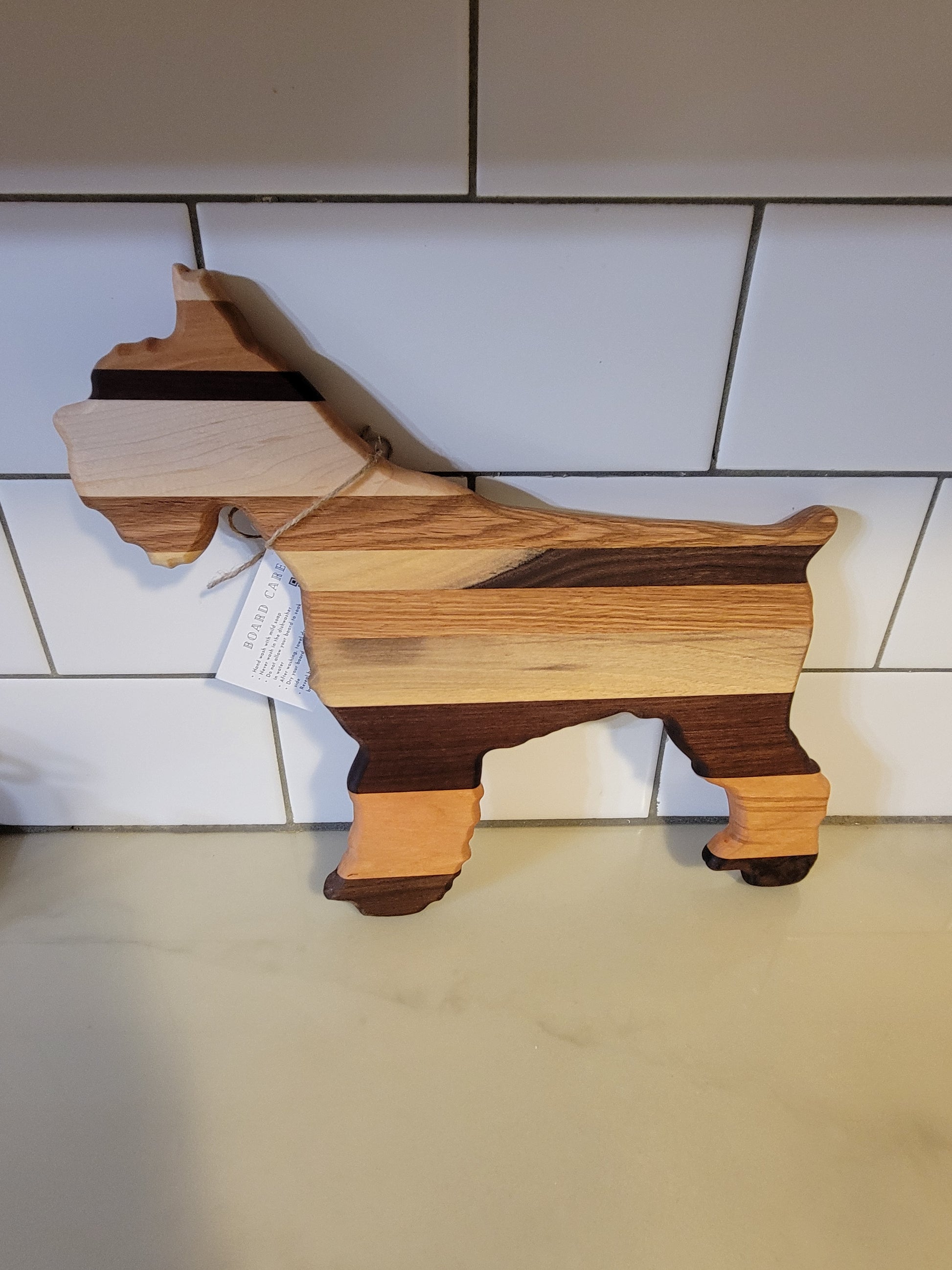 Wooden cutting board with a unique design on a tiled wall.
