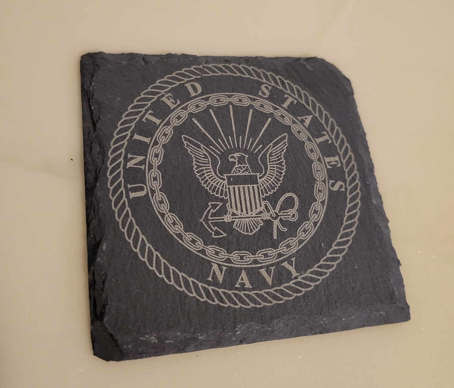 Slate coaster with engraved United States Navy logo.