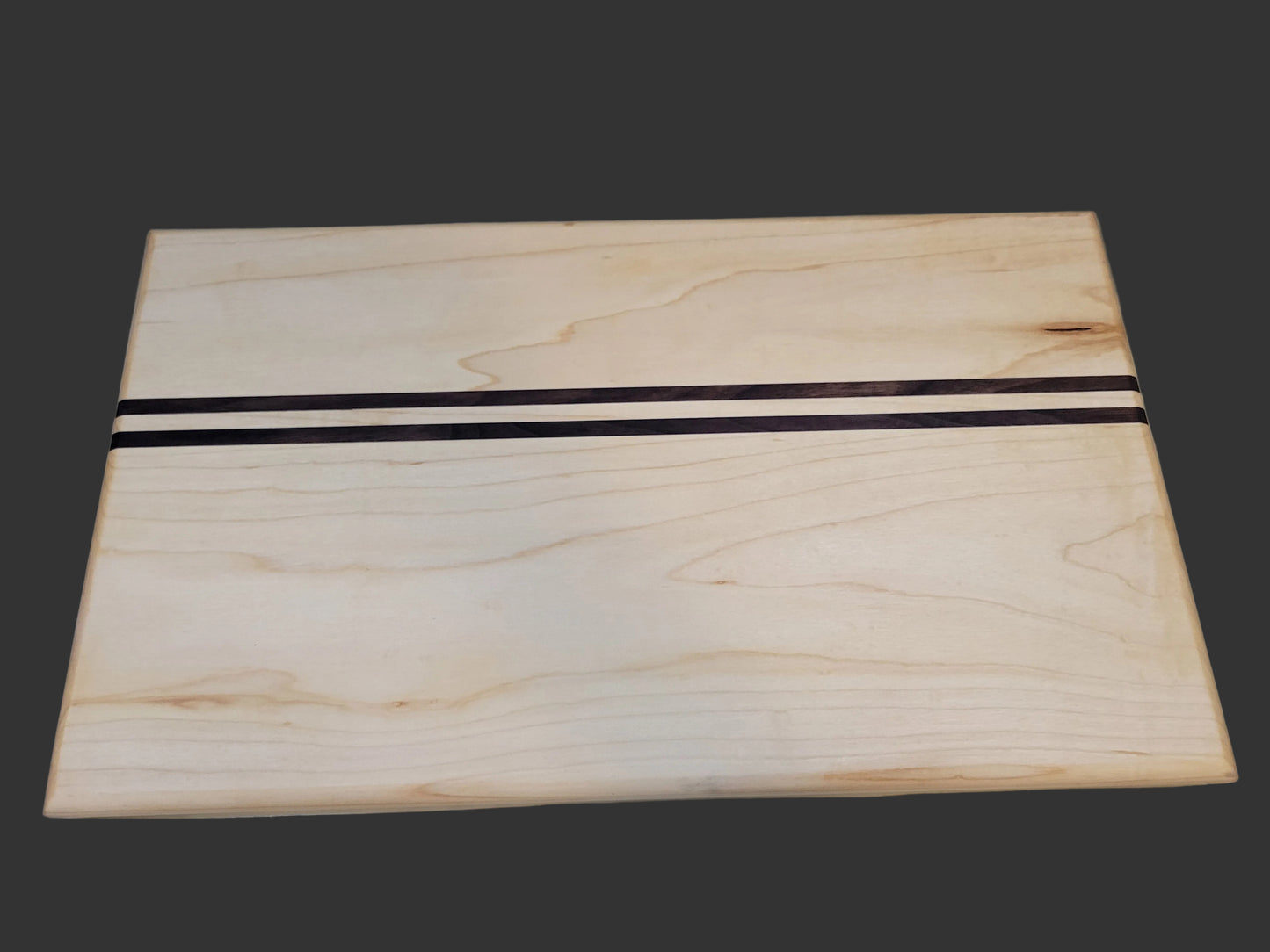 A rectangular light natural wood board with two horizontal dark brown stripes across the center, photographed on a light marble-like surface.