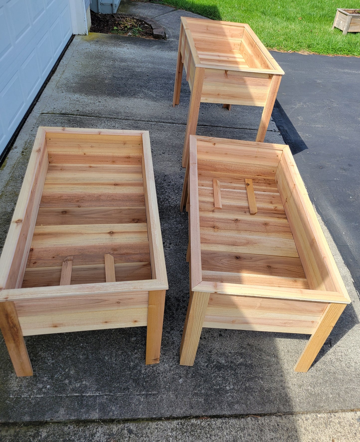 Three wooden planters on a driveway