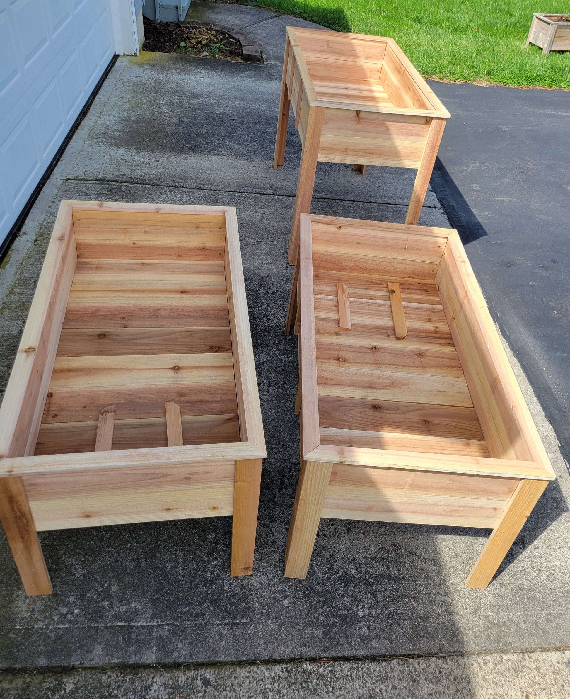 Three wooden planters on a driveway
