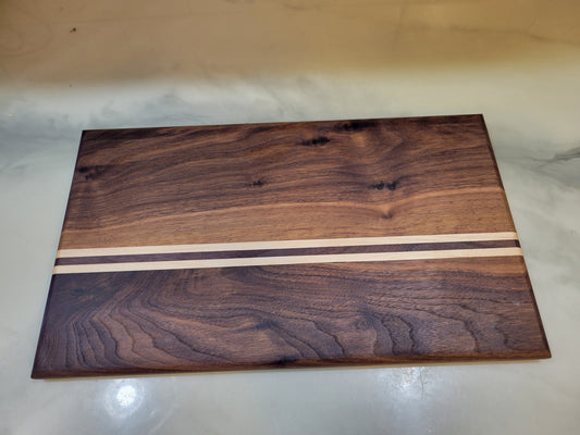 A rectangular wooden board with a dark brown walnut wood grain finish and two horizontal light beige inlay stripes near the center, photographed on a light marble-like surface.